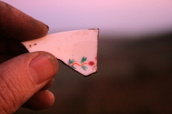 Ceramic shard, in late afternoon sun, from excavation of demolition rubble from E of chimney base